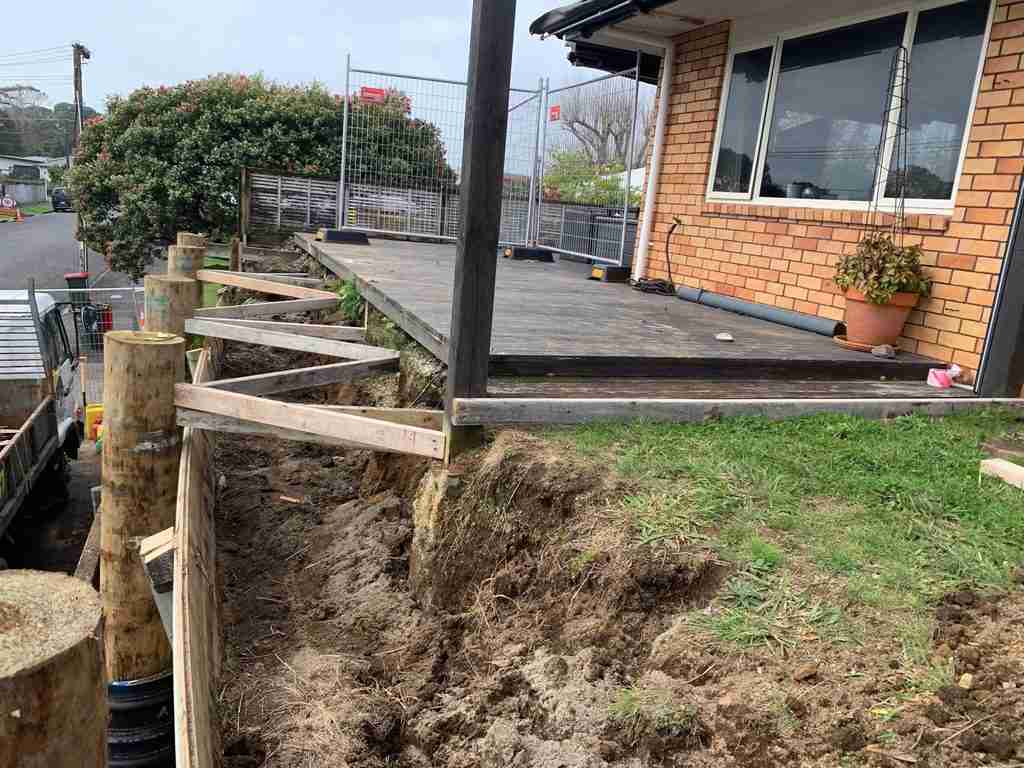 Temporary bracing supporting the ground below the house during retaining wall replacement